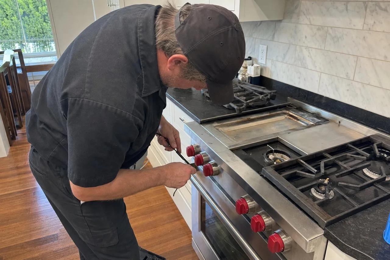 Technician servicing a stainless Wolf range in a Pound Ridge kitchen